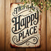 A rustic iron wall sign with carved text that reads This Is My Happy Place mounted on a wooden surface.