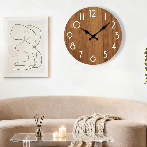 A minimalist wooden wall clock with a dark face hangs above a light beige sofa and glass table.