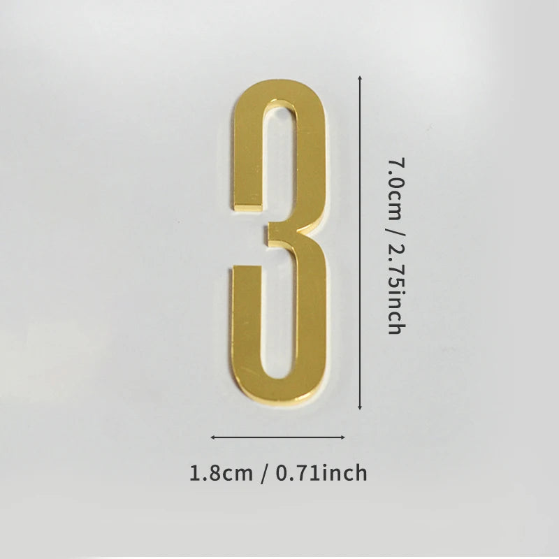 A polished gold house number shaped like the numeral three with a self-adhesive backing.