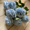 A bouquet of nine realistic light blue silk roses with green leaves.