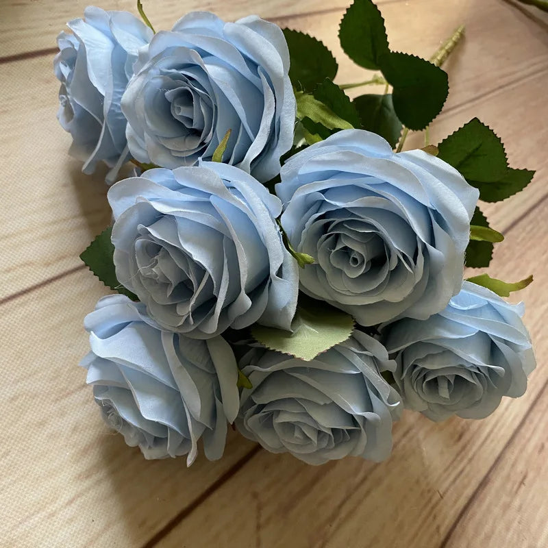 A bouquet of nine realistic light blue silk roses with green leaves.