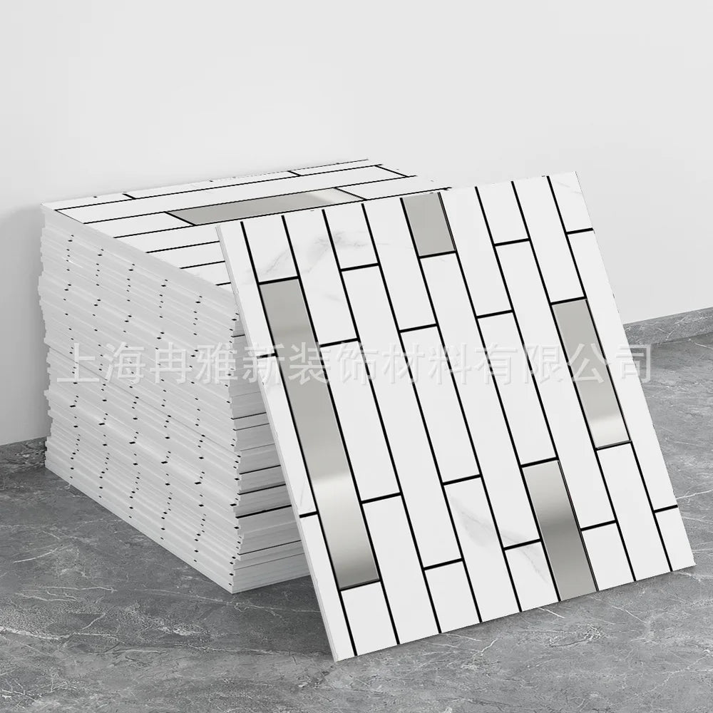 A stack of white marble peel-and-stick tiles with silver and gold accents displayed on a gray surface.