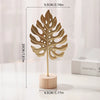 A golden iron ginkgo leaf ornament mounted on a wooden base.