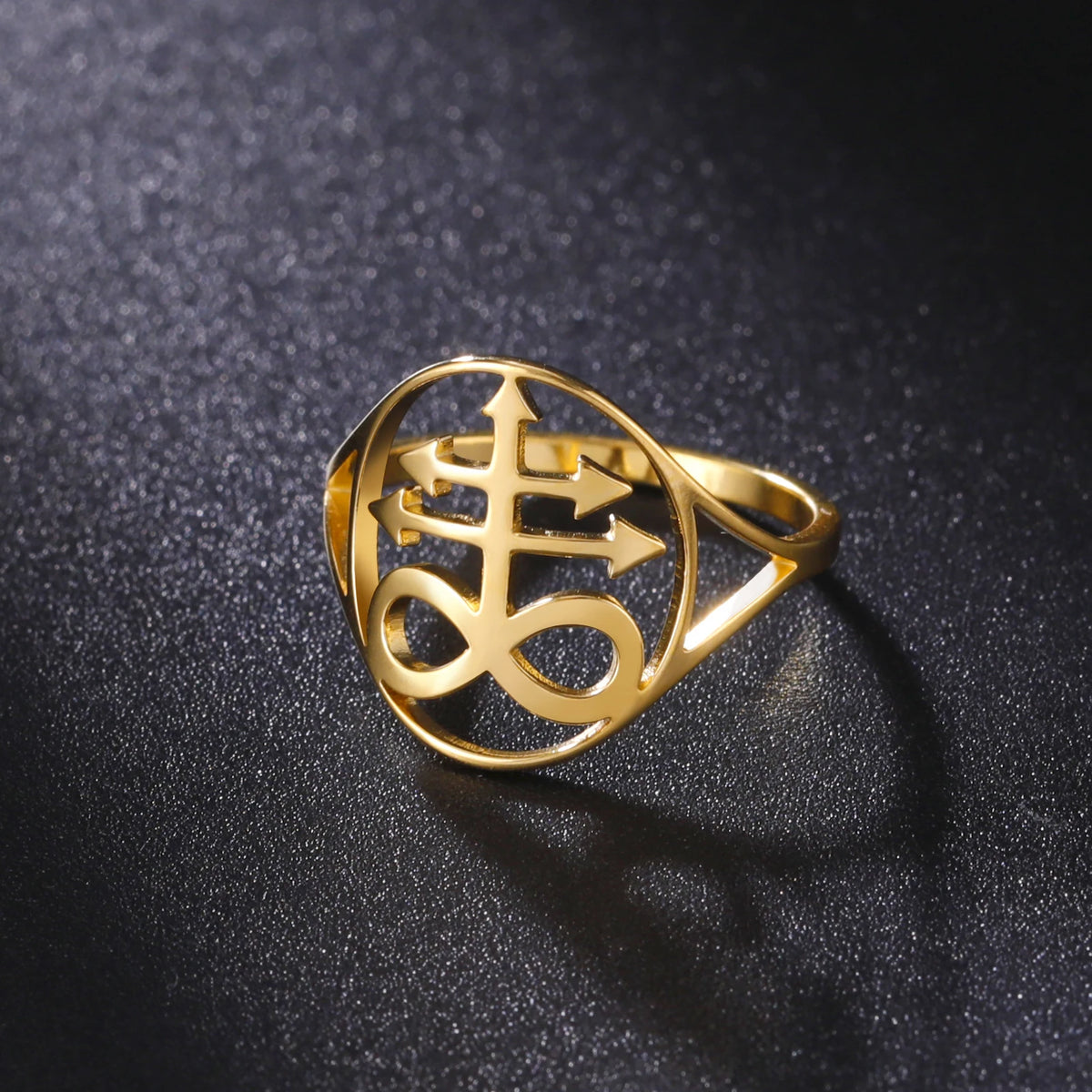 A gold signet ring featuring a Leviathan cross design resting on a dark surface.