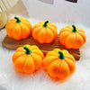 Three bright orange decorative LED pumpkins resting on a wooden board surrounded by white fluffy material.