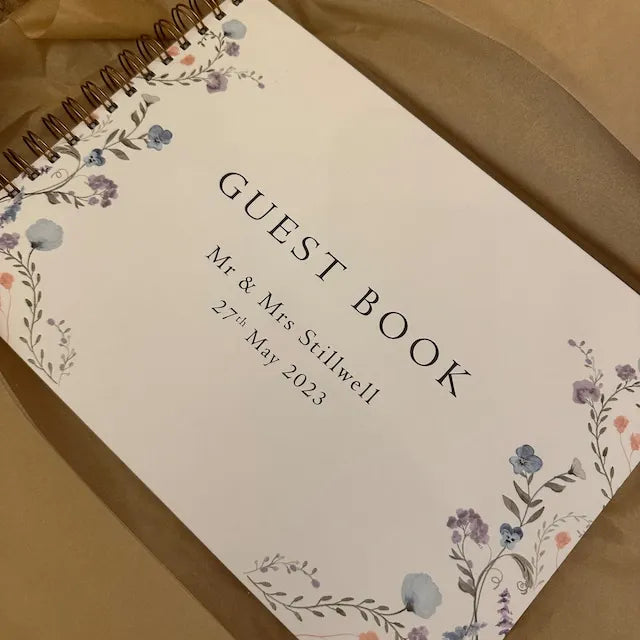 A personalized wedding guest book with a light background and floral watercolor accents, featuring the text Guest Book and a 