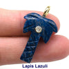 A deep blue lapis lazuli crystal pendant with a gold bail and a clear zircon charm, held by a finger.