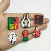 A hand holds several cartoon football shoe charms featuring a number 7 and soccer players.
