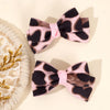 Une paire de pinces à cheveux en velours à imprimé léopard rose et noir.