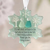 A light mint green acrylic snowflake pendant featuring white tree designs and a message about valuing relationships.