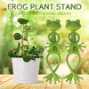 Green frog-shaped plant stand clips used for supporting climbing plants and tomatoes in a white pot.