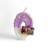 A purple glitter birthday candle shaped like a horseshoe featuring three character figures.