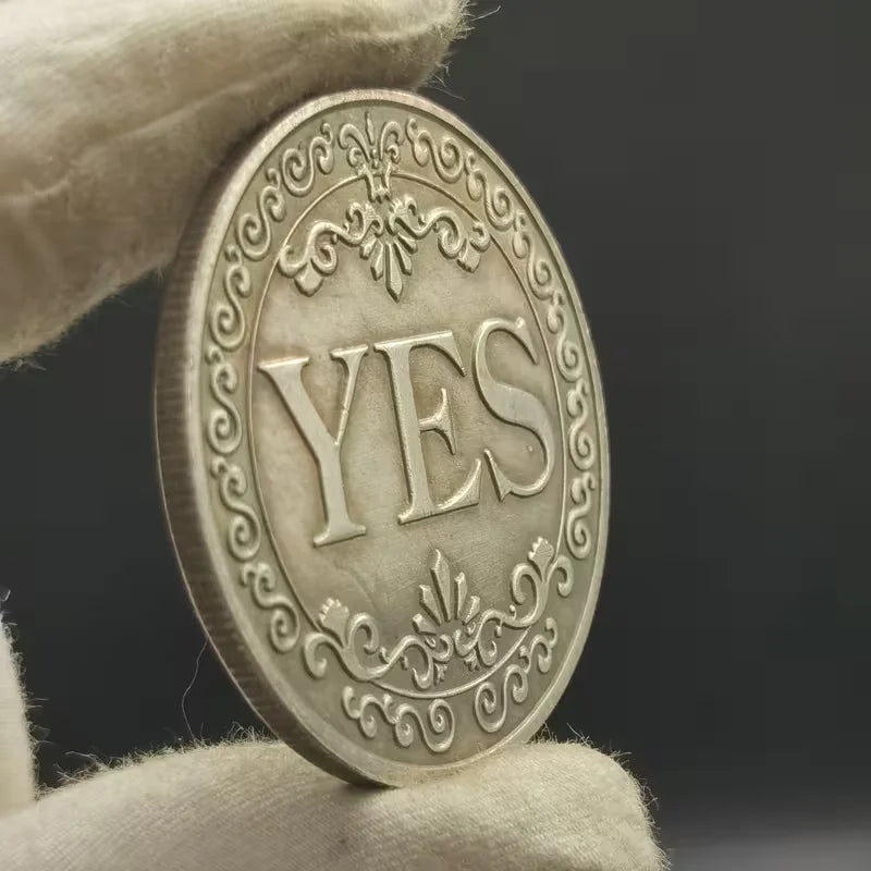An antique silver-gray decision coin with a floral design is held by a hand against a dark background.