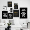 A gallery wall featuring various motivational quotes on black canvas prints displayed above a white sofa.