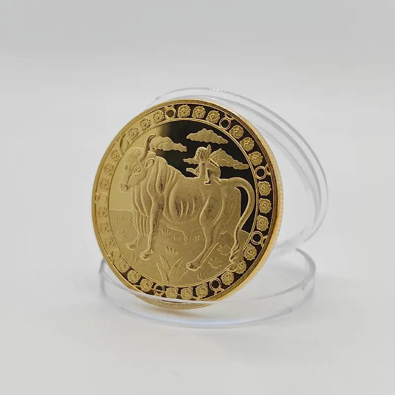 A round gold commemorative iron coin featuring a depiction of a zodiac animal with clouds around the edge.
