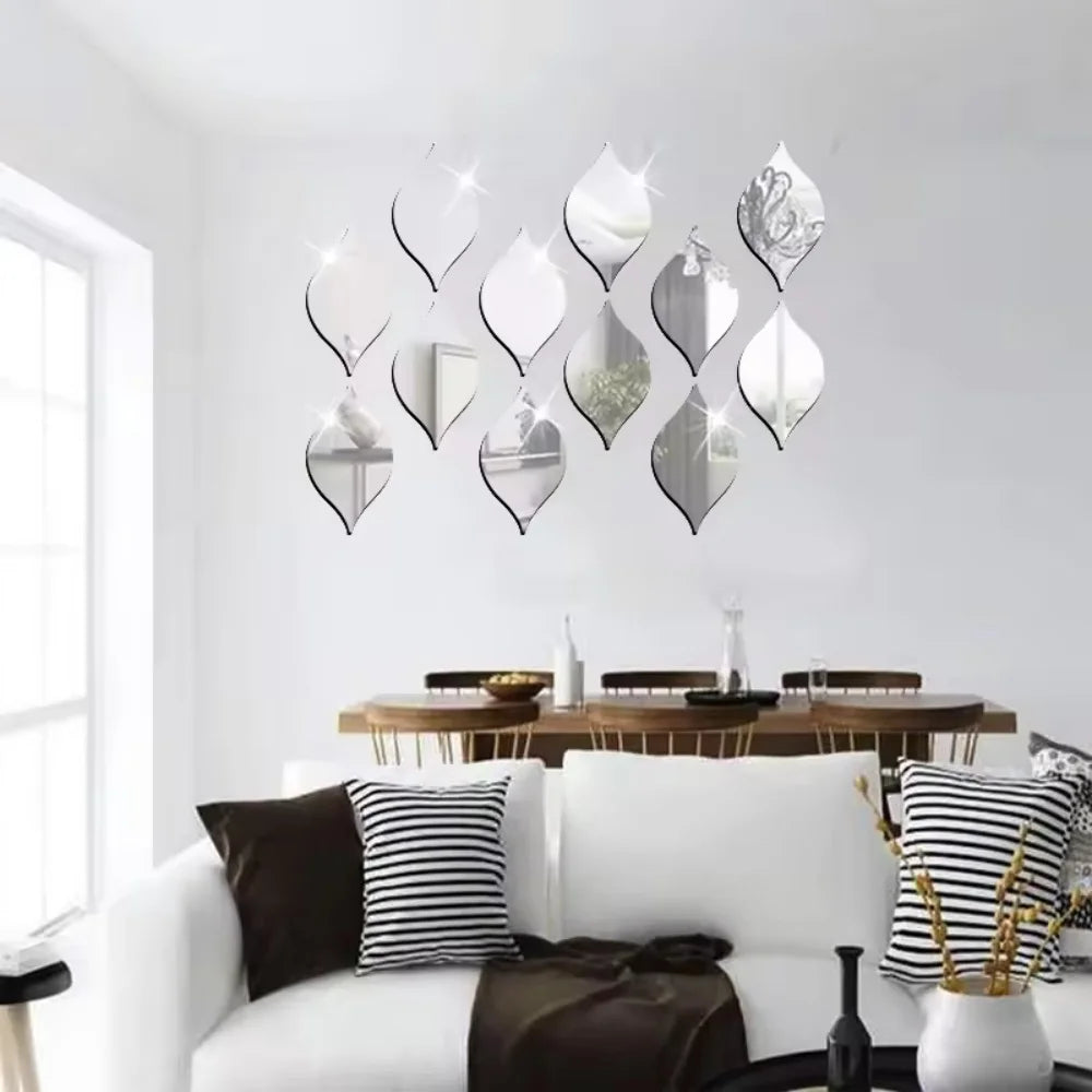 A set of ten reflective acrylic droplet mirror stickers displayed on a white wall above a wooden dining table.
