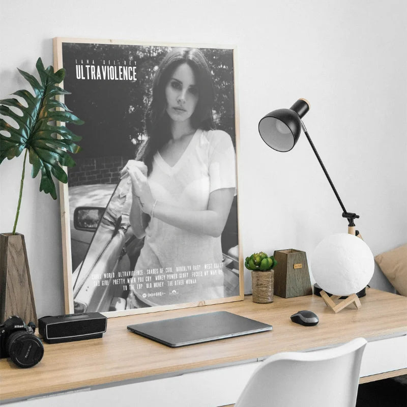 A framed black and white photograph of Lana Del Rey titled Ultraviolence displayed on a wooden desk.