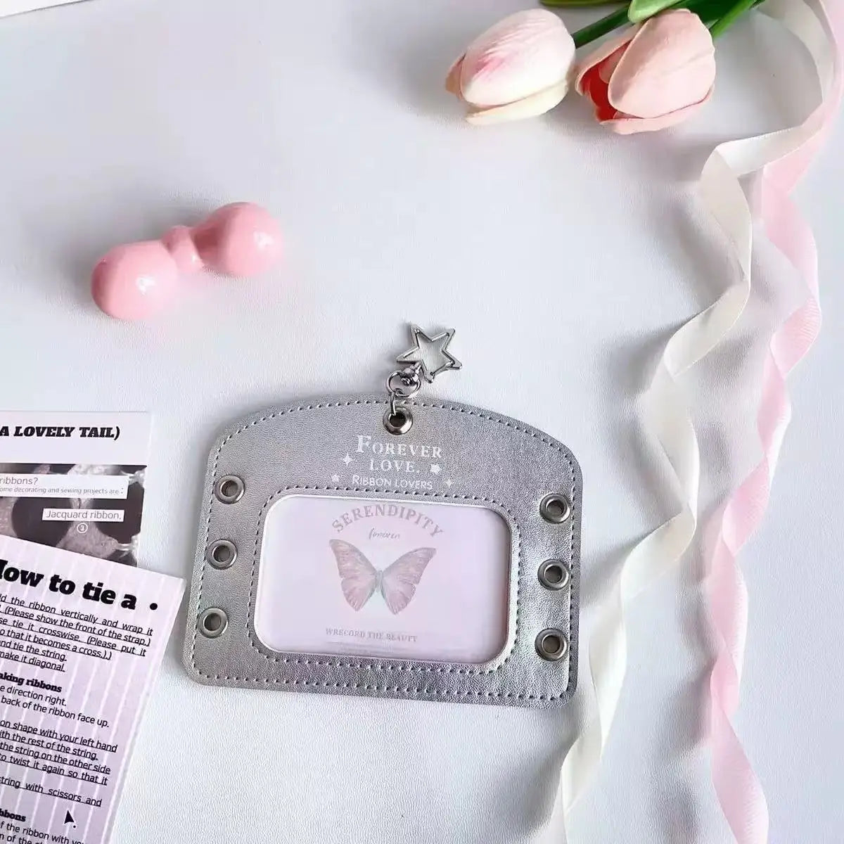 Silver lace PU card holder with a pink bow ribbon keychain resting on a white background.