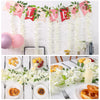 A decorative garland made of artificial white wisteria flowers and pink/red fabric banners for a celebration.