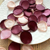 A collection of deep pink and mauve silk rose petals arranged on a white plate.