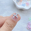 A hand is holding a nail with a silver balloon puppy charm applied to the fingernail.
