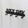 Black metal wall-mounted sign spelling out NICE DAY with seven hooks.