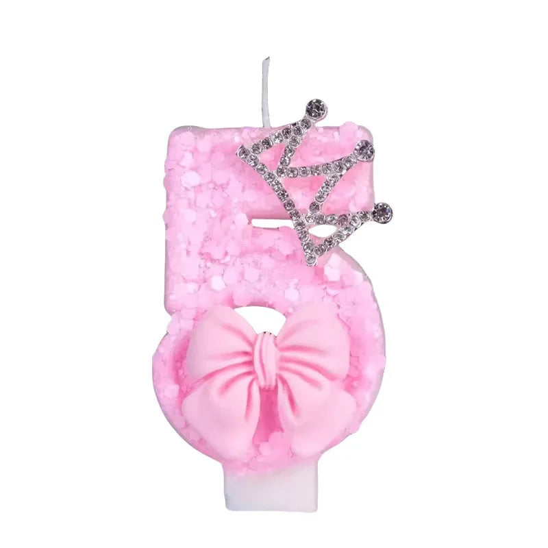 Pink glitter birthday candle shaped like the number 5 with a crown topper
