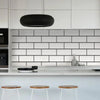 A modern kitchen featuring white cabinetry, a black pendant light, and a subway tile backsplash.