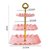 A three-tier plastic dessert stand with pink scalloped plates and a gold-colored vertical support.