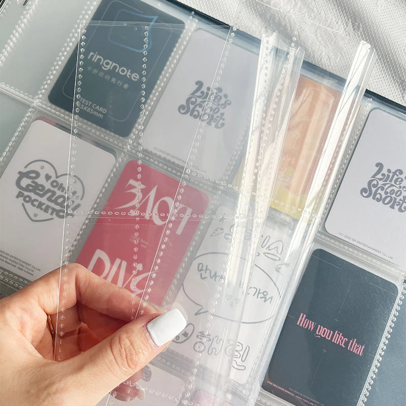 A hand holds a clear plastic grid binder filled with various photo cards and notes.