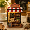 A miniature wooden shop display featuring coffee items and a striped awning, used as a DIY fridge magnet.