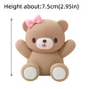 A cute, light brown teddy bear-shaped cake topper with pink accents.