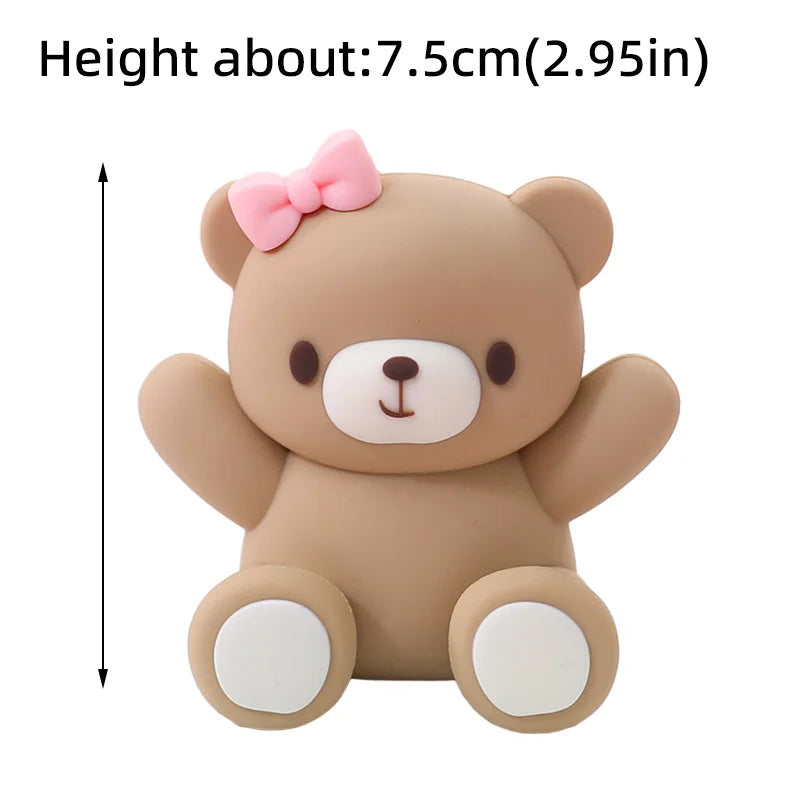 A cute, light brown teddy bear-shaped cake topper with pink accents.