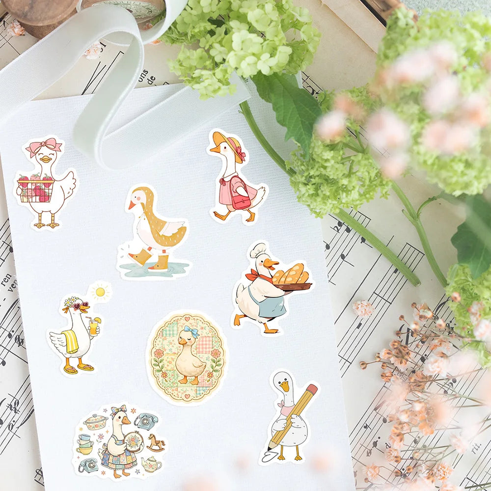 A sheet of white vinyl featuring various funny goose cartoon decals surrounded by green foliage.