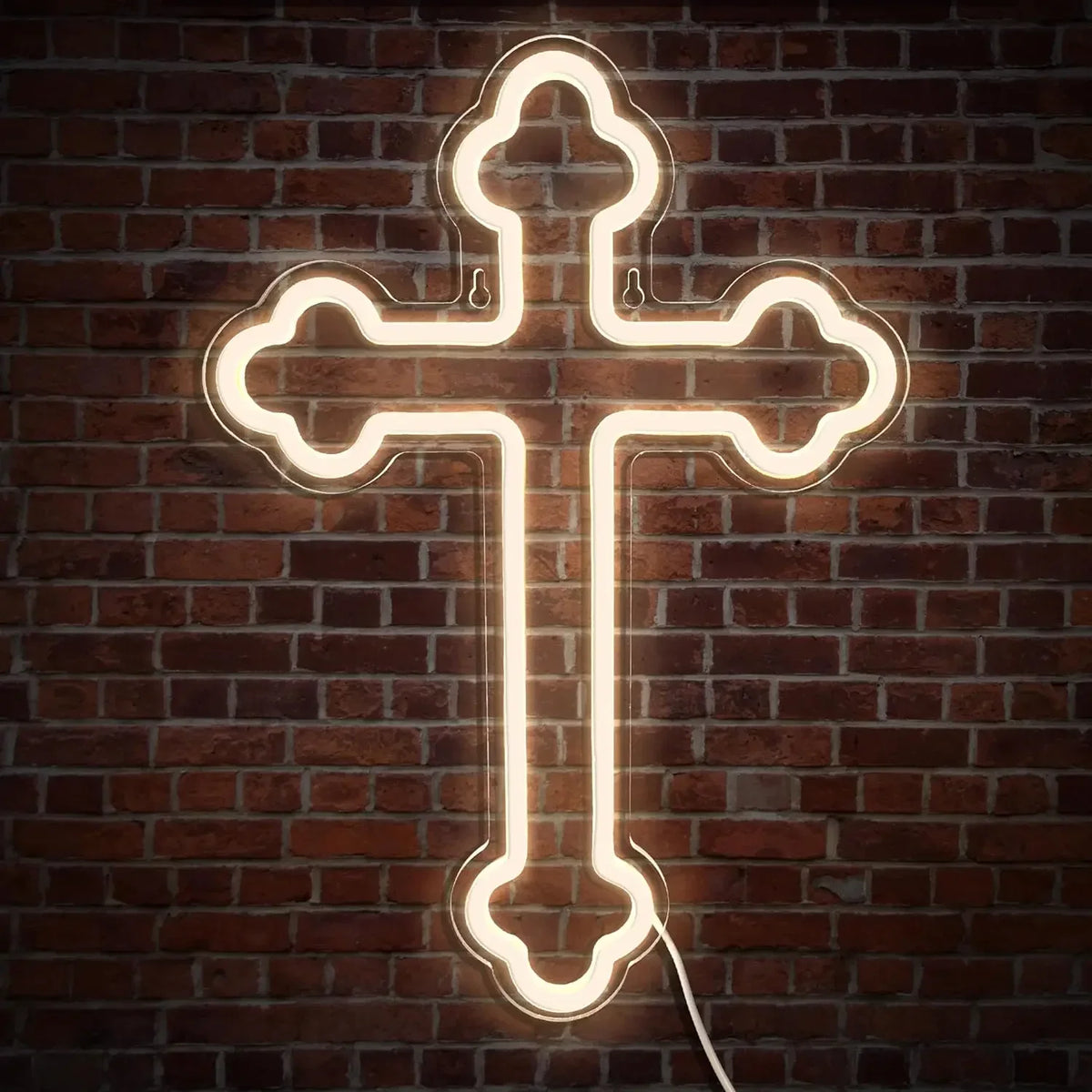 A glowing white neon cross sign mounted on a dark brick wall.