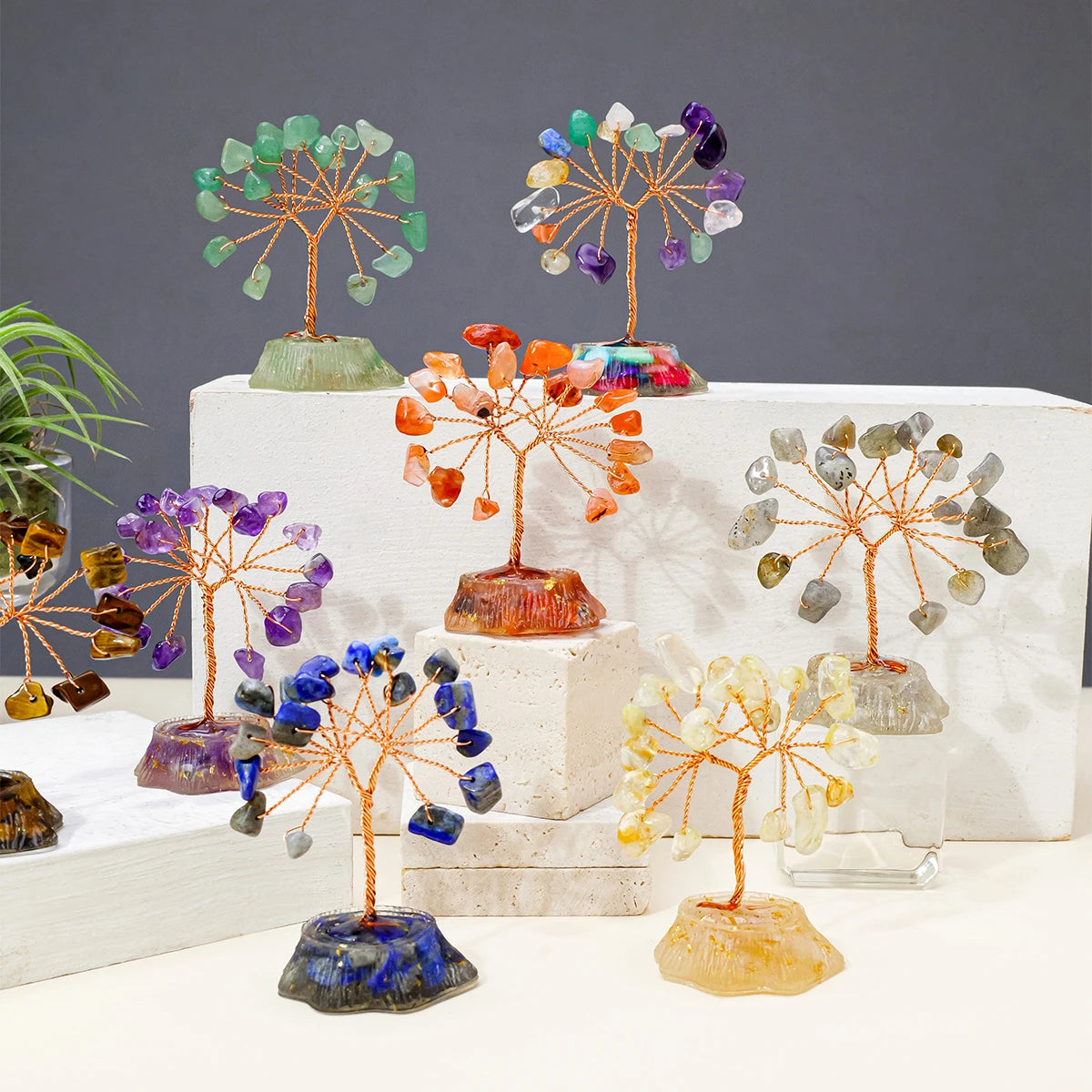 A collection of seven crystal trees featuring various natural colored stones like green, purple, orange, and yellow.