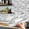 A hand holds a rectangular crystal film marble wall decal against a gray and white stacked tile background.