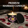 A premium massage candle in a black tin sits on a marble surface surrounded by rose petals.