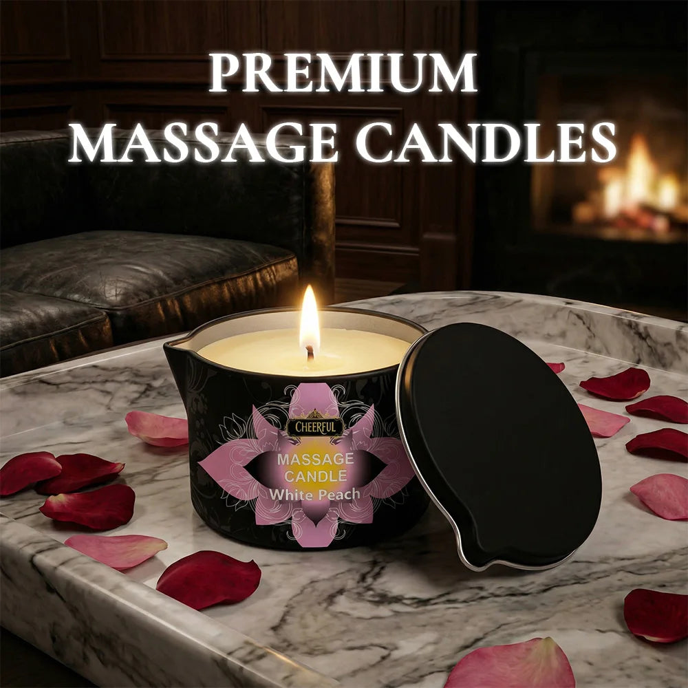 A premium massage candle in a black tin sits on a marble surface surrounded by rose petals.
