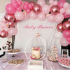 A baby shower setup featuring pink and white latex balloons, confetti, and treats on a table.