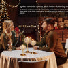 A couple is seated at a table with glowing metal glass candle holders in a romantic, dimly lit setting.