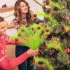 A woman and a man decorating a Christmas tree with green spruce branches and red berry ornaments.