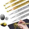 A collection of extra-fine point acrylic paint pens in gold and silver colors are shown with a hand painting on a dark surfac