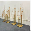 A set of eight gold metal candelabra with glass candles displayed on a gray carpet.