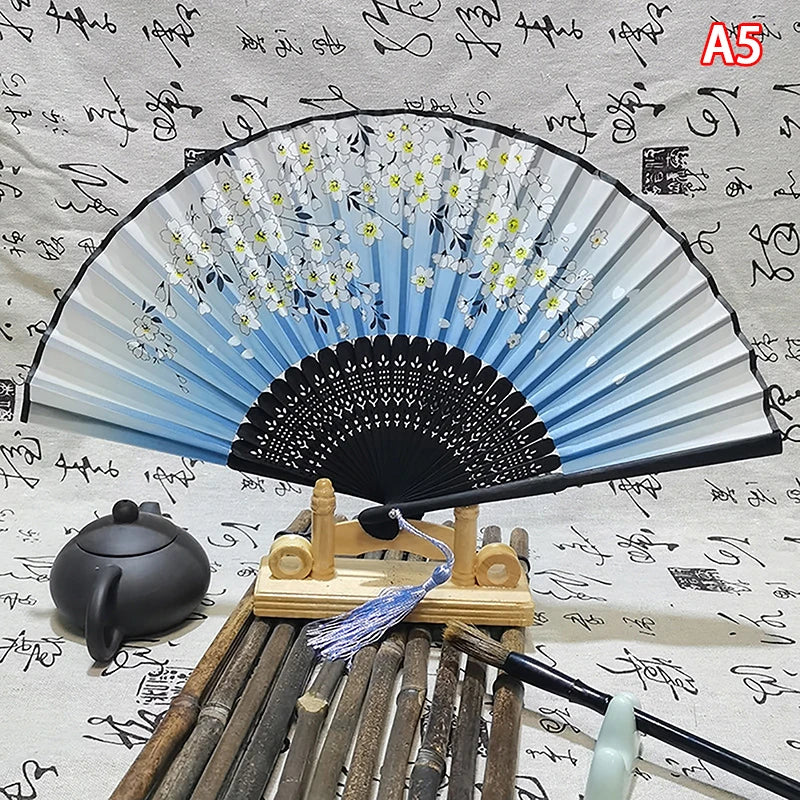 An elegant vintage Chinese folding hand fan displayed with bamboo sticks and a dark ceramic object.