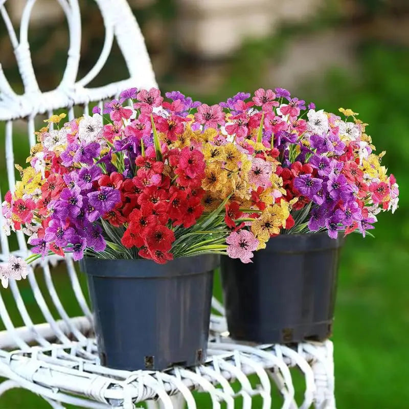 A bouquet of artificial violet flowers in various shades of pink, purple, and yellow potted in dark containers on a white lat