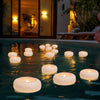 Bougies flottantes illuminent une piscine sombre au crépuscule avec une lumière chaude et lumineuse.