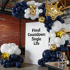 A balloon arch display featuring navy blue, white, and gold balloons in a crown shape for a countdown event.