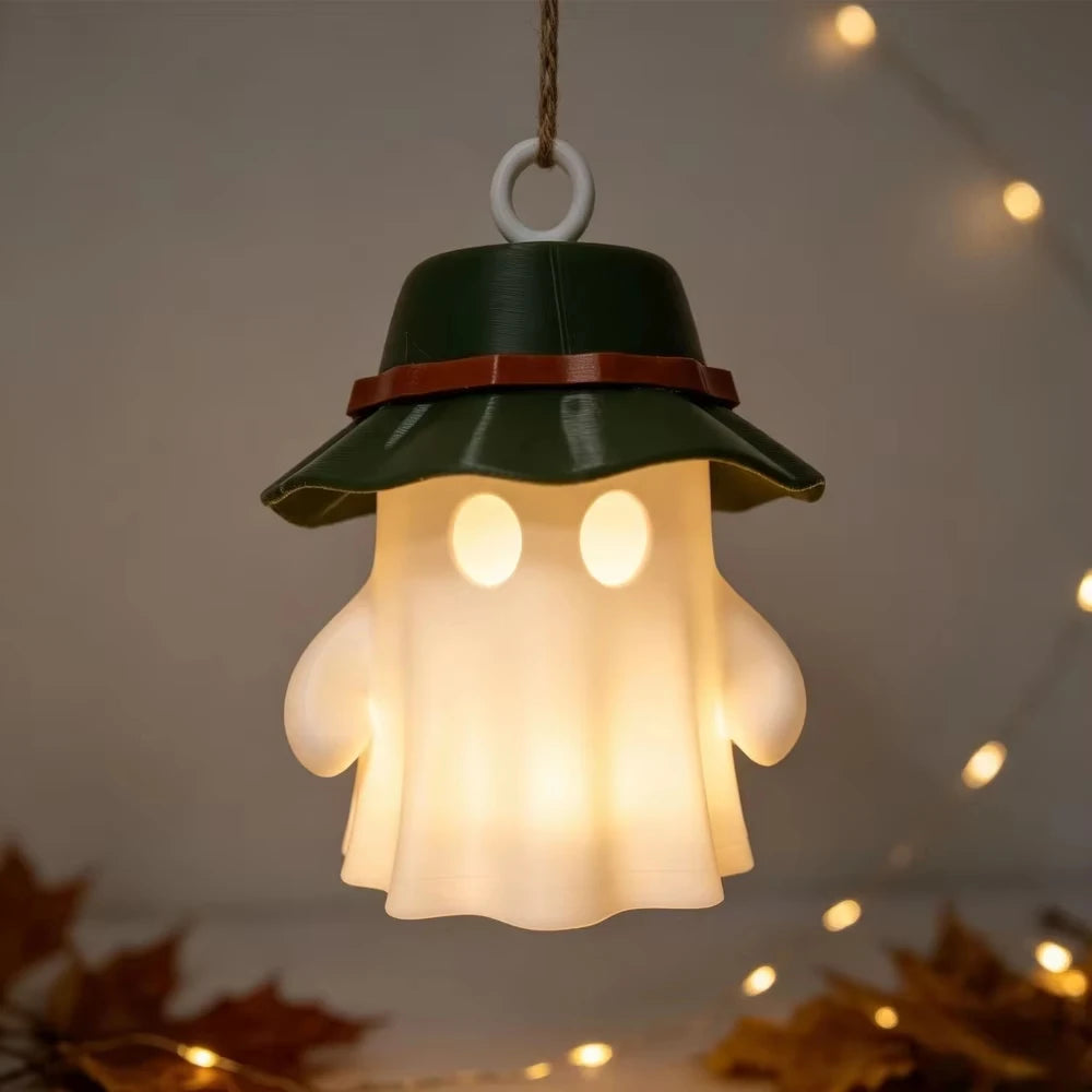 A camping ghost night light hangs, featuring a green hat and a warm glowing face.