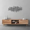 A black geometric metal wall art sculpture is displayed above a light wood cabinet.
